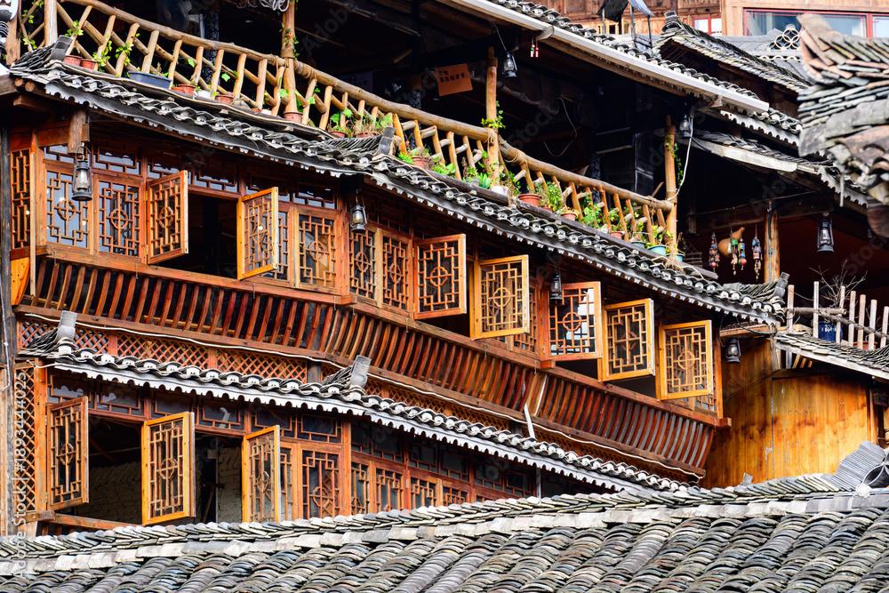Obraz premium A traditional Miao village building in Guizhou, showcasing the distinct brownish-yellow fir timber framework and the layered gray ceramic roof tiles, embodying the rustic architectural style.