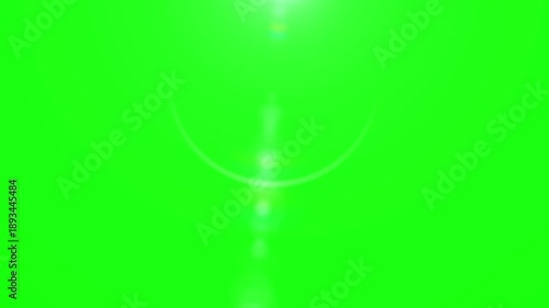 Bright cinematic lens flare effect shimmering gently downwards over a vibrant chroma key green screen background providing perfect visual space for creative post production video compositing needs