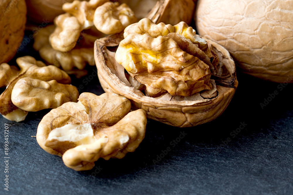 Fototapeta premium Macro view organic ripe walnut harvest on black stone background.