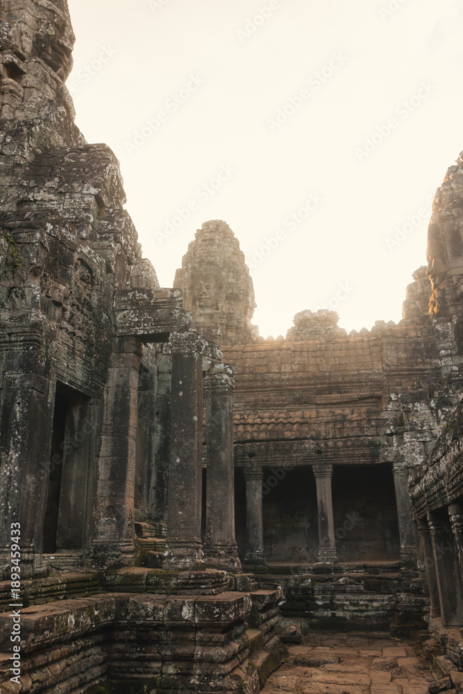 Naklejka premium Ancient Bayon Temple Courtyard at Sunrise with Stone Faces in Cambodia