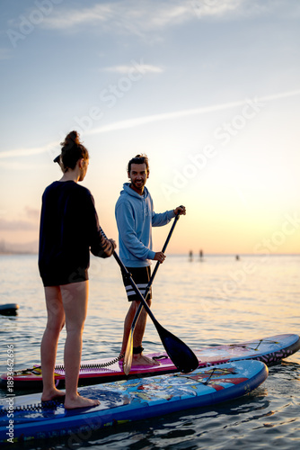 Foto Paddle boarders moving calmly across the water at sunset, mindful outdoor moment