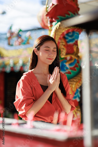 Canvas Print Young asian woman praying in front of temple shrine