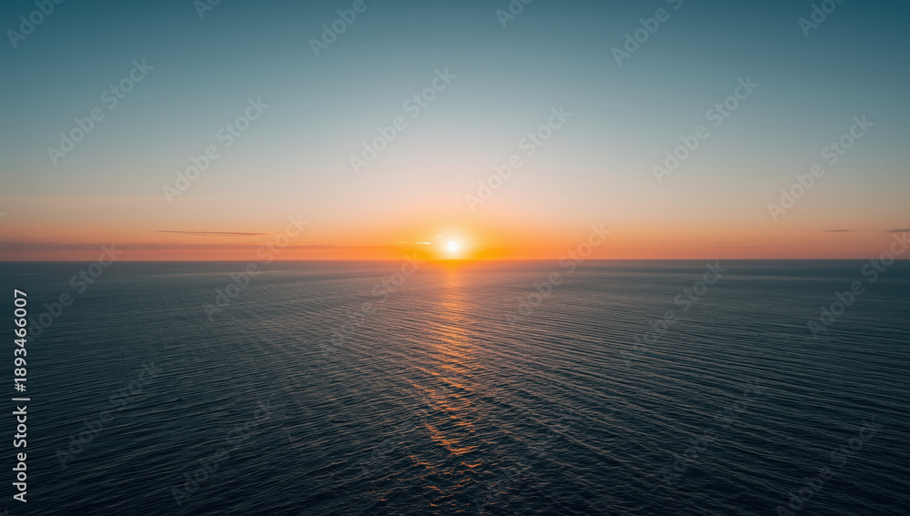 Fototapeta premium Serene ocean sunset, horizon glow, warm sky, calm water
