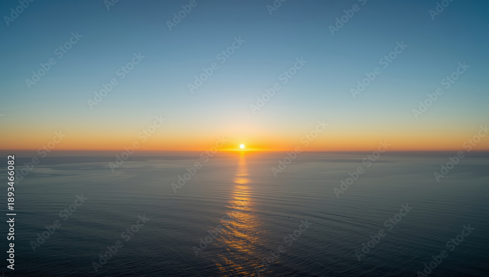 Fototapeta premium Serene ocean sunset with sun reflecting on calm water and soft gradient sky
