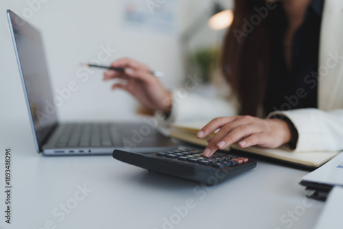 Businesswoman calculating finances using calculator and laptop