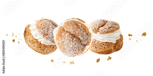 Cream puffs, pastry from choux covered sugar powder with crumbs flying isolated on white background. Sweet dessert for coffee break