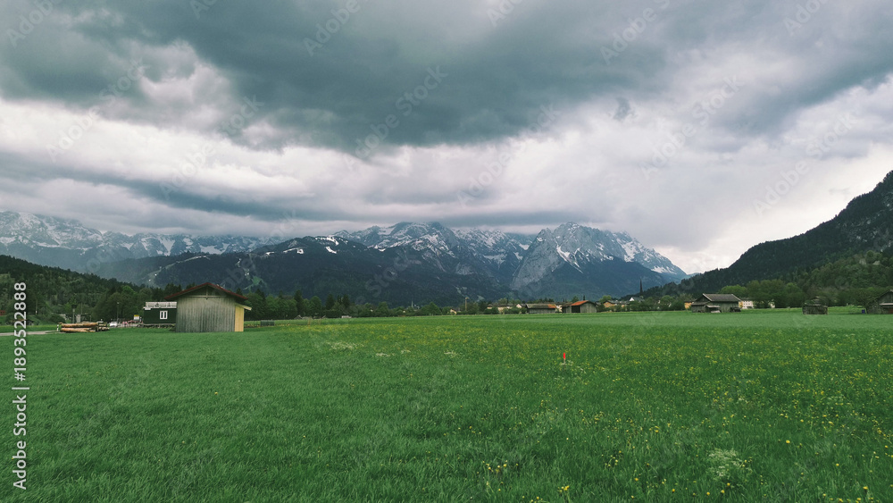 Obraz premium Countryside village below high snowy mountains