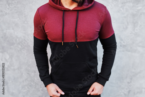 Canvas-taulu Man wearing maroon and black hoodie standing against gray wall