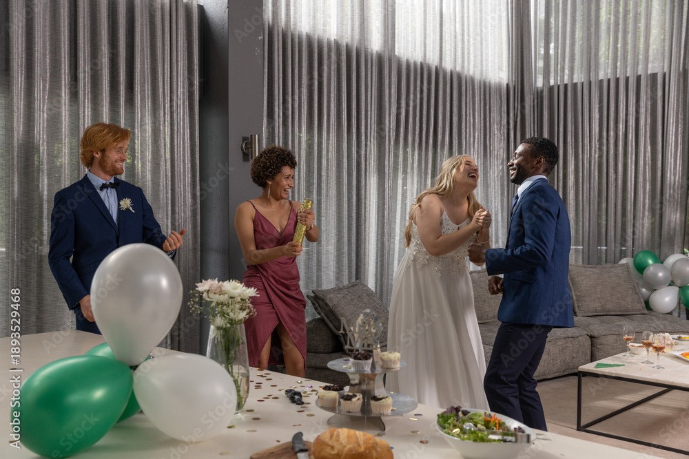 Fototapeta premium Diverse couple dancing and laughing in decorated reception hall with balloons, cupcake stand