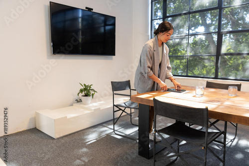 Foto Woman standing by wooden table in meeting room arranging tablet near glasses, co