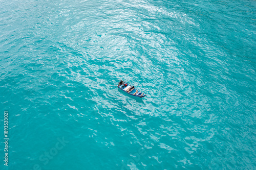 Aerial view of a small boat adrift on the turquoise sea, creating a striking contrast against the vast expanse of water, Kalleesa, Socotra, Yemen.