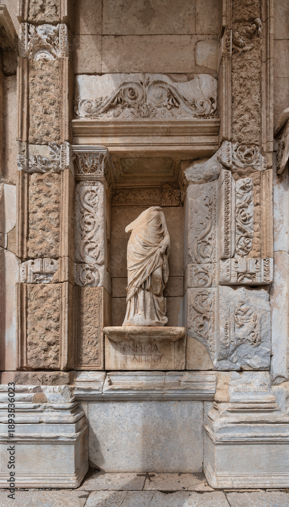 Obraz premium Headless statue of Ennoia at the Library of Celsus, ancient Roman ruins in Ephesus, Turkey. Intricate stone carvings and historical architecture