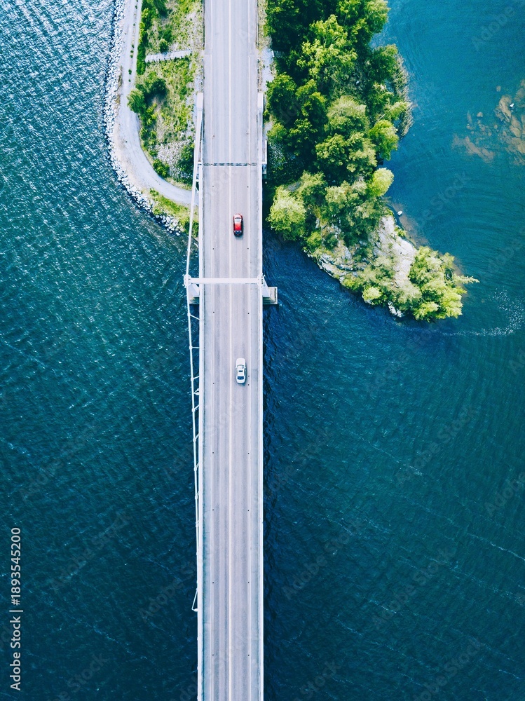 Obraz premium Aerial View of a Scenic Bridge Connecting Land and Water Amidst Lush Greenery in Finland