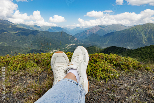 Close-up of women's feet in sneakers on the background scenic views on mountain and valley  Beautiful landscape, travel background, wallpapers and banner.