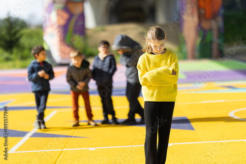 Obraz na plátně Girl feeling excluded by peer group on colorful playground