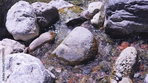 Crystal clear water flowing over river stones in a mountain stream