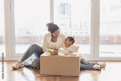 Obraz na plátně Mother and daughter eating lunch in new unfurnished apartment