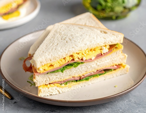 Delicious Sandwich with Egg, Ham, and Lettuce on Plate