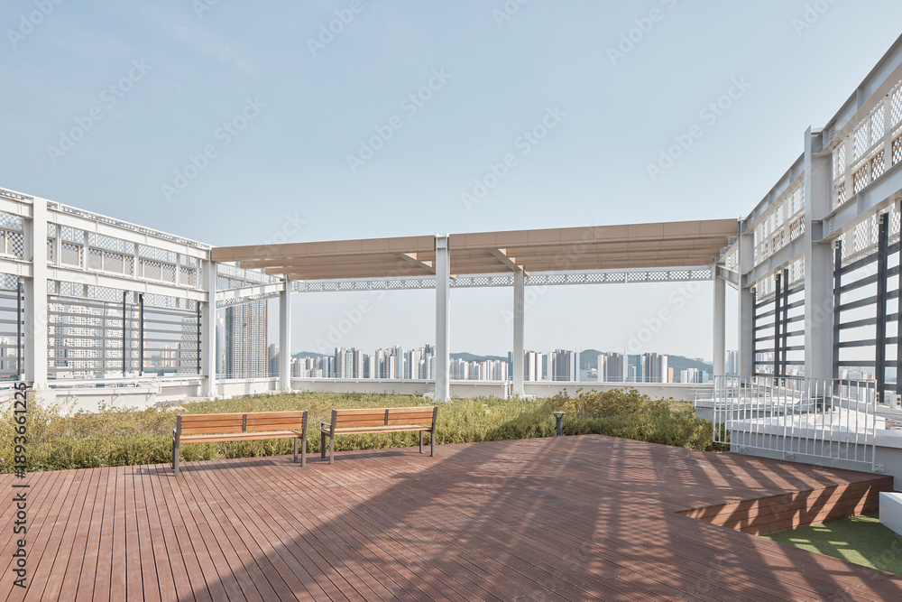 Fototapeta premium Modern rooftop terrace with wooden deck and city skyline view