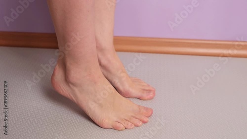 Set of exercises for the feet: Standing on your toes. Side view. Woman performing heel raises, lifting body weight onto toes to strengthen feet, ankles, and improve balance and lower leg stability.