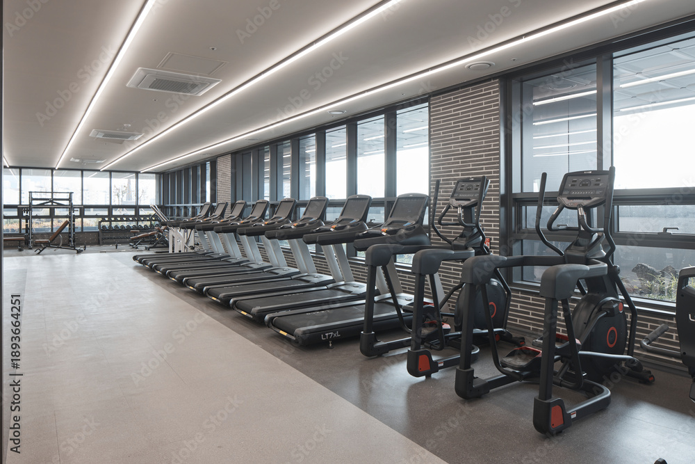 Fototapeta premium Rows of modern treadmills in a bright high-end fitness center