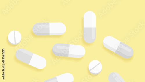 Scattered white and gray capsules and pills on a soft yellow background