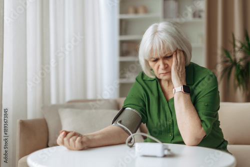 Bilde på lerret Senior caucasian woman sitting with blood pressure monitor on arm at home, elder