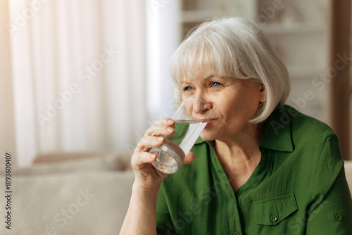 Tableau sur toile Senior caucasian woman drinking water at home, elderly female staying hydrated a