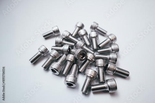 Pile of stainless steel socket head cap screws on a white background.