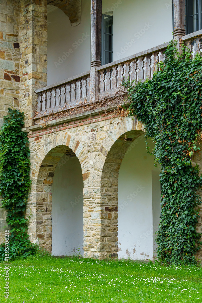 Fototapeta premium close up of architectural details, old stone wall with arched opening and green ivy