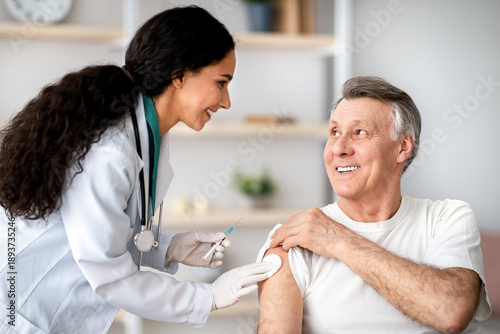 Canvas Print A health professional prepares to give a vaccine to an older man in a clinic