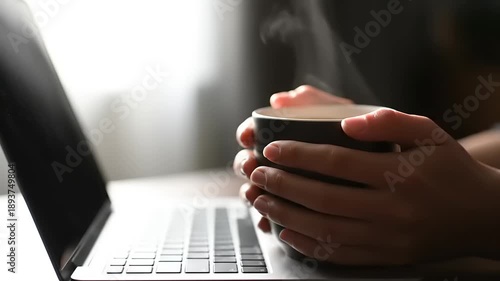 Person Holding Steaming Coffee Mug While Working on Laptop