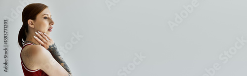 Captivating young woman with intricate tattoos in a minimalist setting exuding confidence and beauty