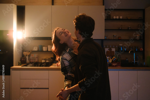 Romantic couple sharing a joyful moment in a cozy kitchen at night with warm lighting