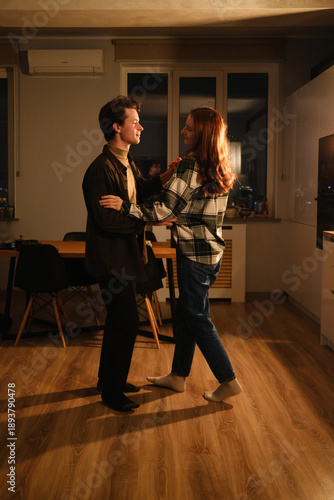 Couple dancing in a cozy kitchen at night, warm lighting, connection and joy in a home