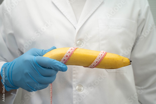 Male doctor stands holding a banana, penis health.