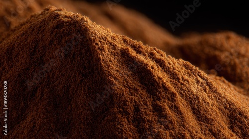 Close-up of a pile of brown powder. the powder appears to be finely ground and has a rough texture. the color of the powder is a warm, earthy brown.