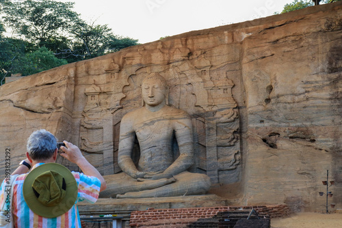 Wallpaper Mural A gray-haired man takes a photo of a Buddha statue in a temple in Thailand. Torontodigital.ca