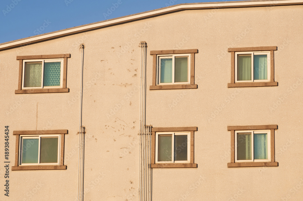 Obraz premium Sunlit Residential Building Facade With Repeating Windows