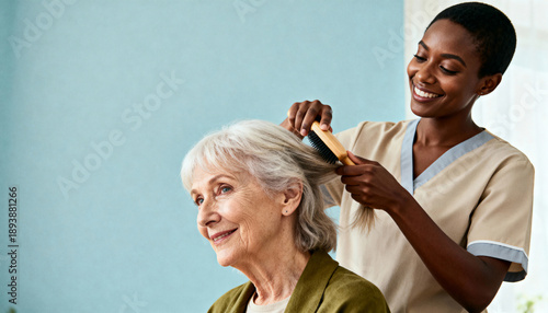 Smiling caregiver brushing a senior woman's hair. Young Black nurse providing support and personal care to an elderly patient. Elder care and assisted living concept