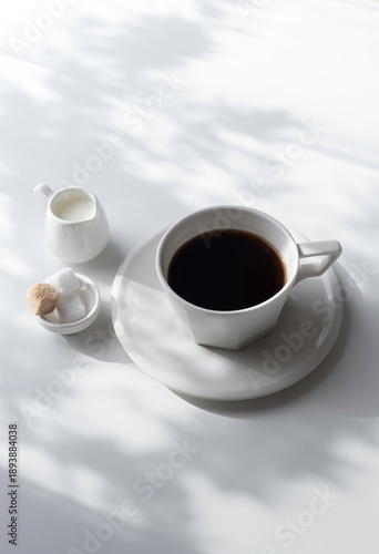 Tableau sur toile Vertical photo of black coffee with creamer and sugar cubes on white background,