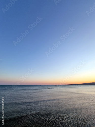 Εκτύπωση καμβά Open sea view at dusk with small boats on horizon