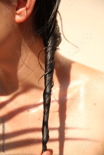 Wet braid of dark hair against bare shoulder