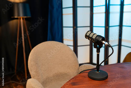 Podcast setup features a microphone and chair in a recording space with a warm light source and decorative background elements