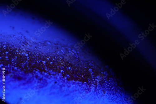 Bild auf Leinwand Abstract macro shot of blue liquid bubbles and a thin fluid thread