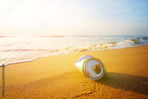 Crumpled beer can on sand beach at sea. Discarded broken beer can at seashore. Environmental pollution, sea water pollution. Rubbish on beach. Clean beach from trash. Empty soft drinks cans trash.