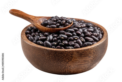Wooden bowl filled with black beans, a wooden spoon overflowing with beans