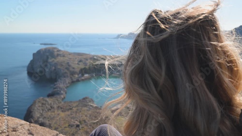 Woman sitting on the acropolis wall overlooking the landscape near Lindos on Rhodes island in Greece