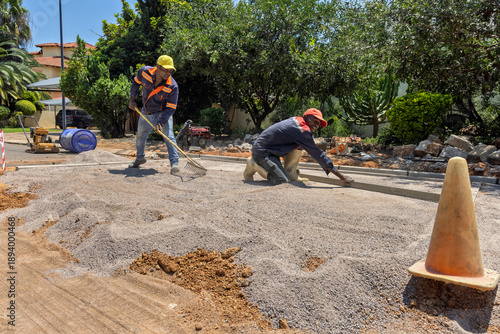 Two african american construction workers leveling gravel during road paving