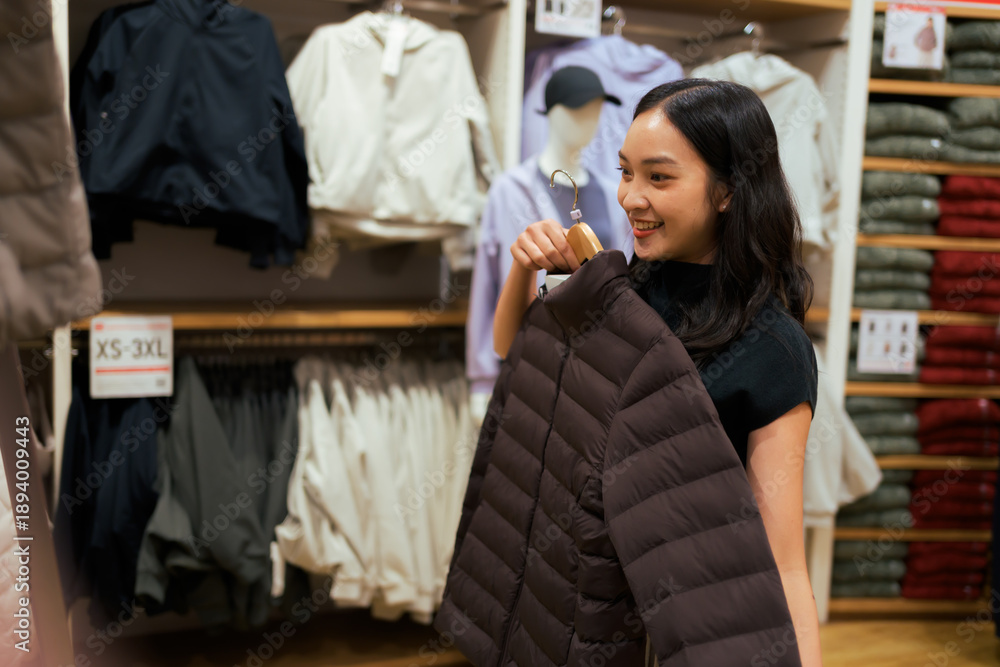Fototapeta premium Asian woman shopping for winter jacket in clothing store